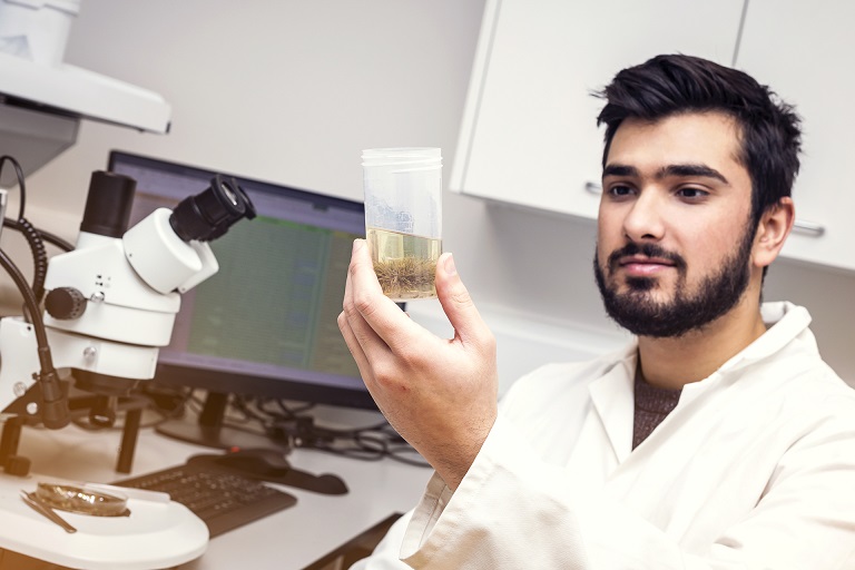 Lab technician at Malin House holding a beaker with a sample