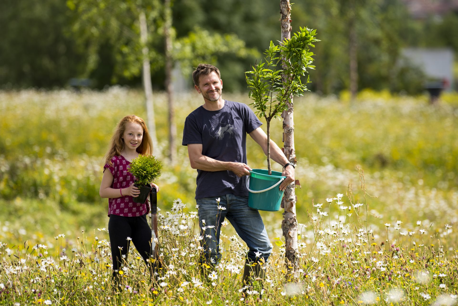 Young man and girl holding tree in field ready for planting 