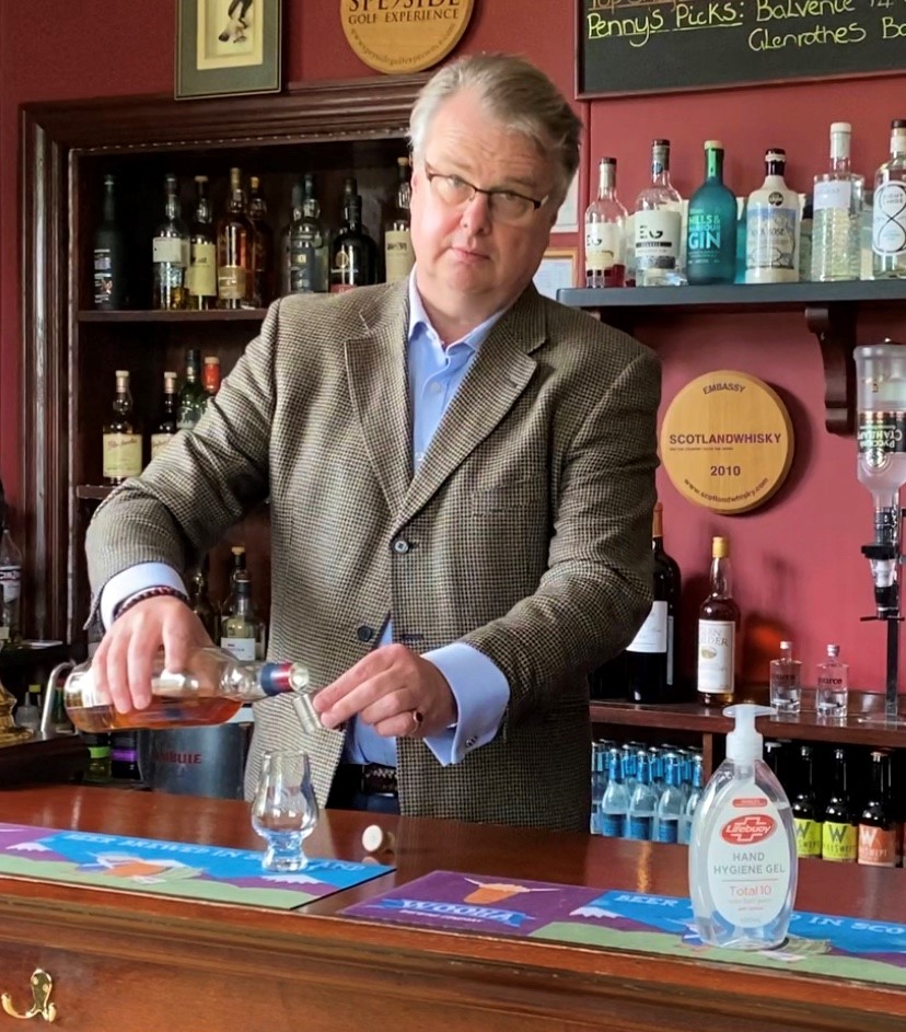 gavin Ellis standing behind hotel bar pouring a measure of whisky